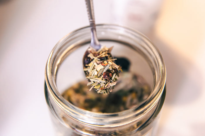 Jar of loose-leaf herbal tea with teaspoon